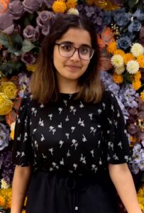 A picture of someone wearing glasses in front of a floral background